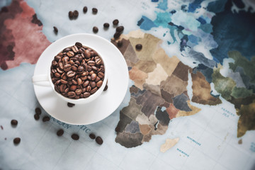 roasted coffee bean in white coffee cup on vintage world map