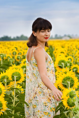 Naklejka na ściany i meble Brunette woman in sundress in sunflower field