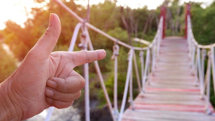 Close up male hand pointing walking path on rope bridge over mangrove forest with mild sunshine in...