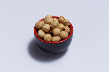 Front view of hazelnuts inside a red bowl isolated on white background.