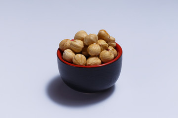 Front view of hazelnuts inside a red bowl isolated on white background.