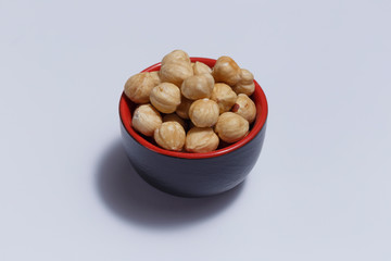 Front view of hazelnuts inside a red bowl isolated on white background.