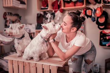 Cute dark-eyed woman playing with fluffy white dog