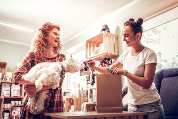 Cheerful shopping assistant giving some food for dog to smell