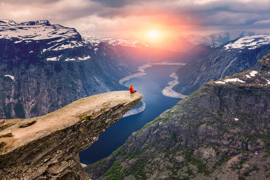 Norway, A woman sits on the mountain's cliff edge of Trolltunga