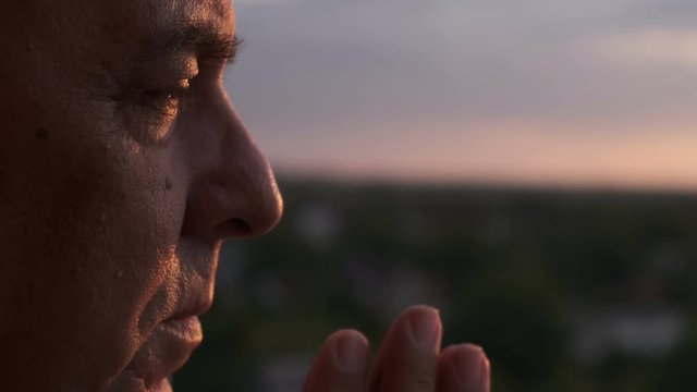 Elderly man praying at sunset, close up