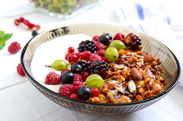 Yogurt, granola, fresh berries in a bowl on a white wooden background. Delicious and healthy breakfast. Proper nutrition. Dietary menu.