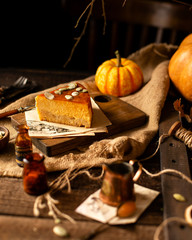homemade tasty slice of pumpkin orange cheesecake on wooden board on rustic brown table