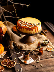 homemade tasty pumpkin orange cheesecake on wooden cake stand on rustic brown table