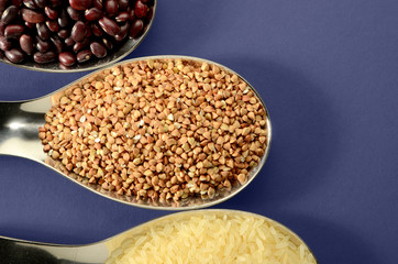 BEANS RICE BUCKWHEAT IN A SPOON, ON BRIGHT BACKGROUND