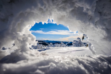 Beautiful winter mountain landscape of Giant mountains, Czech republic. Krkonose mountains in a winter day. Bright blue sky, sun star shining and snow lines and powder snow. Frozen trees.