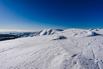 Beautiful winter mountain landscape of Krkonose National Park, Giant Mountains, Czech Republic. Labsky dul, Snezne jamy, Kotel and Snezka peaks covered in snow, Brigh day, blue sky, outdoor activity.