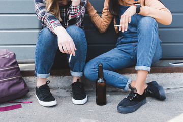 cropped view of teens smoking cigarettes, holding beer and sitting © LIGHTFIELD STUDIOS