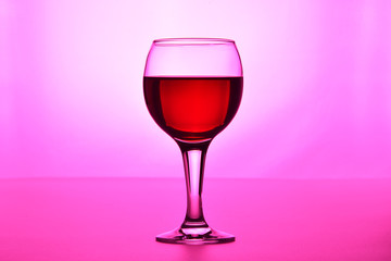 A glass of red wine on a pink background