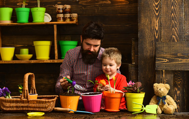 Flower care watering. Soil fertilizers. bearded man and little boy child love nature. Family day. Greenhouse. Father and son. Fathers day. happy gardeners with spring flowers. Be successful
