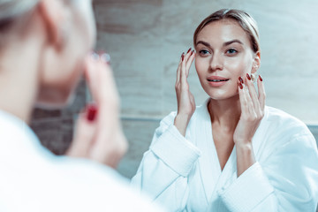 Appealing lady with red nails applying face cream