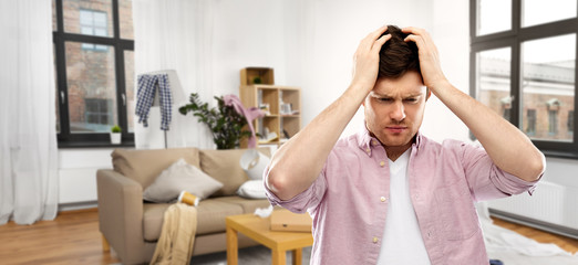 cleaning, housework and stress concept - despaired man suffering from headache over messy room...