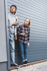 african american boy and blonde teenager looking away, smoking cigarettes and holding beer