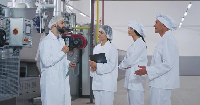 Meeting time at manufacturing industry engineer and the professional workers have a conversation engineer explaining the plan of the day while holding a map they wearing a special uniform for