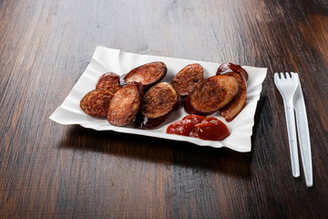 fried sliced sausage -  dish on a paper tray