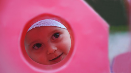 Funny little boy look through the hole in rose plastic fence