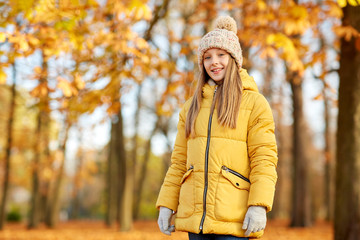 childhood, season and people concept - happy girl at autumn park