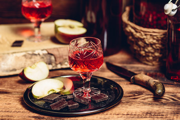 Glass of homemade currant nalivka and chocolate with apple