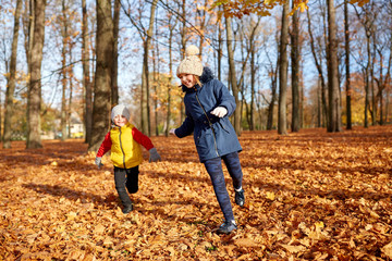 Fototapeta premium childhood, season and people concept - happy children running on fallen leaves at autumn park