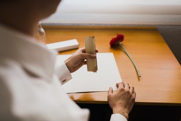 Elegant man knots a roll of paper with a message to put it in a bottle.
