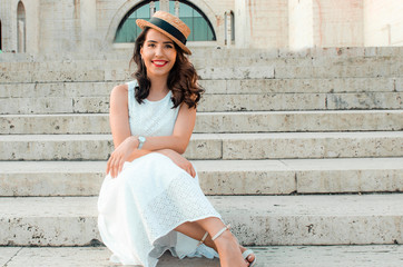 young woman in white dress outside sitting and smiling
