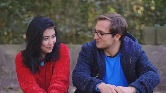 shy young Couple On First Date in the park,Man Tenderly kissing on cheek woman