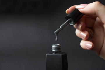 gray shellac nail polish dripping on black background with copy space