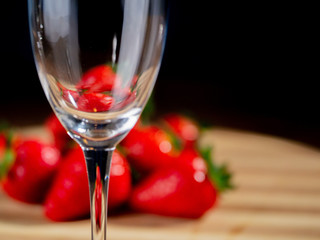 Still life, Champagne flute in focus, Red strawberries out of focus in the background.