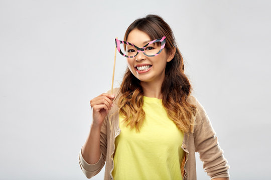 party props, photo booth and people concept - happy asian young woman with big glasses over grey background