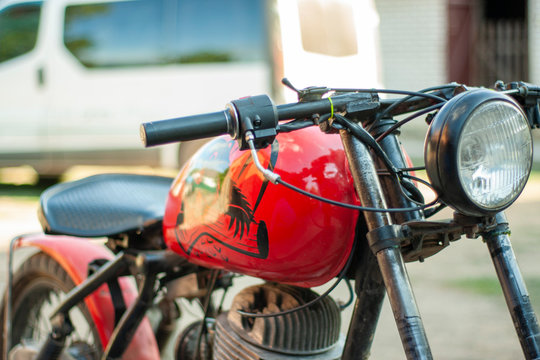 Old renovated red-colored motorcycle with a beaver stick on a tank.
