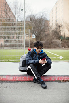 Young man using smartphone on sidewalk