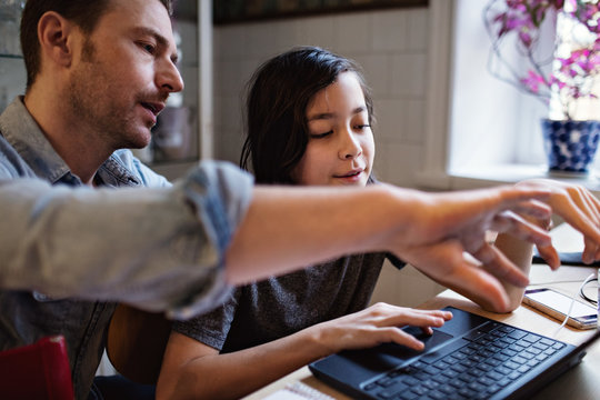 Father assisting son in using laptop for homework at home