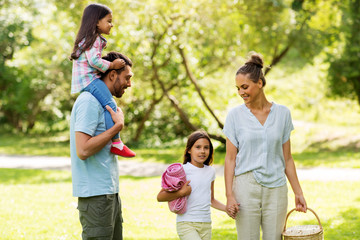 Fototapeta premium family, leisure and people concept - happy mother with picnic basket, father and two daughters in summer park