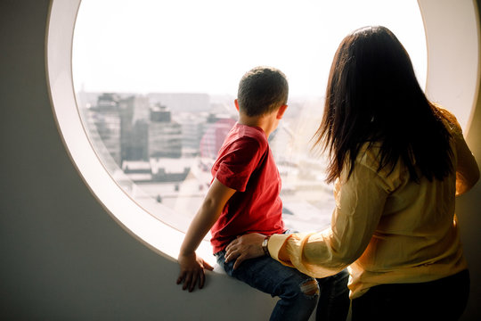 Mother and son looking through window