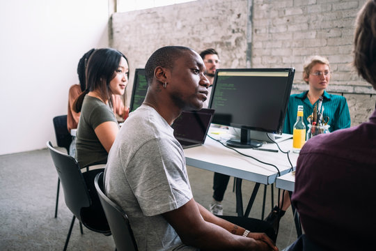 Confident male and female IT professionals sitting in board room during meeting at creative workplace