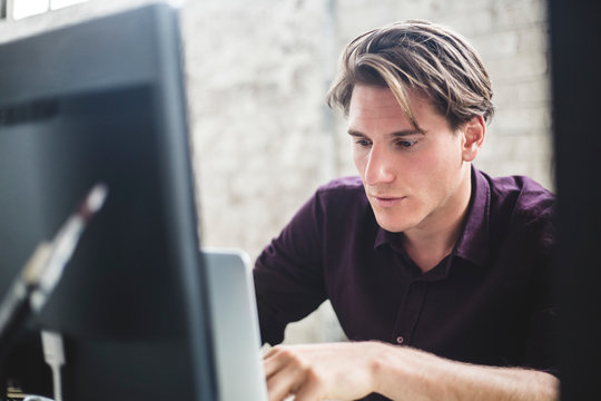 Male computer programmer using laptop while working in office