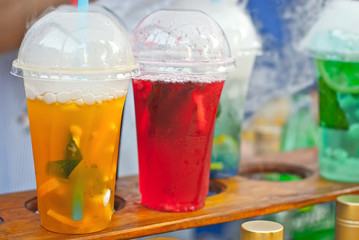 Multicolored fruit drinks close-up. Non-alcoholic drinks in plastic cups at the festival. Cocktails with juice and greens. White smoke is steaming with cocktails.