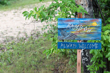 rainbow welcome sign in the middle of forest having greenery in the background 