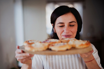 Mature woman serving homemade cakes on a wooden tray