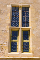 Fototapeta na wymiar Belle fenêtre à vitraux sur mur de pierre