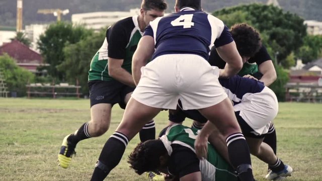 Men playing a game of rugby on a sports field. Rugby players in action on pitch during the match.