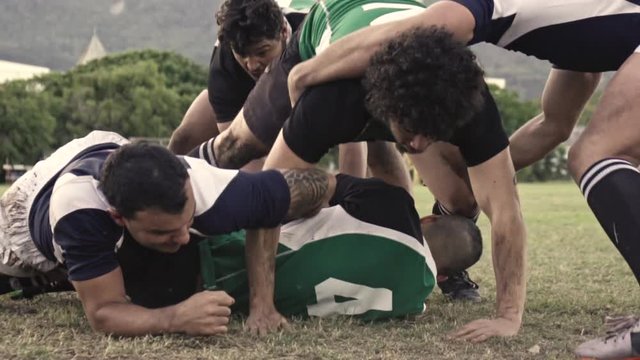Rugby players tackling with the opponents for the ball. Rugby players fight for the ball on the field.