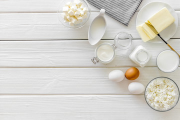 Fresh dairy products for breakfast with milk, cottage, eggs, butter, yougurt on white wooden background top view mock up