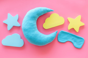 Night sleep concept with moon, clouds, stars toys and blindfold on pink background top view