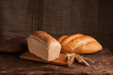 loaf of bread, concept of home food close up on wooden table and black background